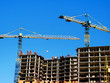 © fotolian121212 - Two building cranes and building under construction. Construction Background. Construction site with cranes on sky background.