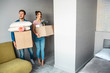 © estradaanton - Young family couple bought or rented their first small apartment. Beautiful people enter room and carry boxes with stuff. Excited and amazed.