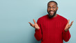 © wayhome.studio  - I know nothing. Horizontal shot of friendly looking black man spreads hands, gestures actively while explains something to interlocutor, stands over blue background, mock up space aside, has no idea