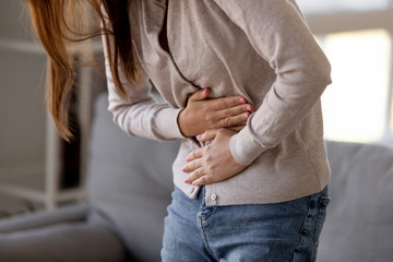 Close up woman holding belly, feeling pain, health problem concept