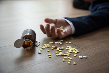 Close-up hand of stressed business man suicide by taking overdose on wood ground