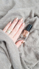 Female hands with long nails with golden brown nail polish