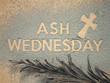 Ash Wednesday concept - Ash Wednesday words and a cross formed out of ashes. There’s a dry palm leaf under them.