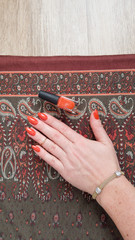 A female hand with long nails holds a bottle with a orange nail polish