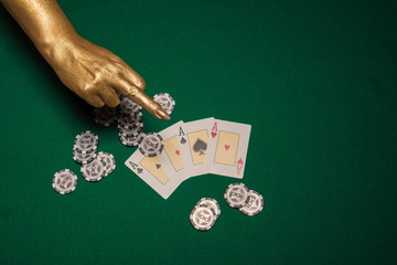 Green card table with cards and chips and gold female hands