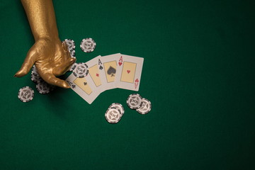 Green card table with cards and chips and gold female hands