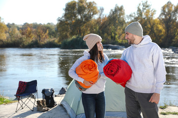 Sticker - Young couple with sleeping bags near camping tent outdoors. Space for text