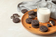Plate with chocolate sandwich cookies and milk on table. Space for text