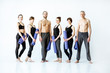 Group of young athletic people in sportswear standing with fitness mats on the white background