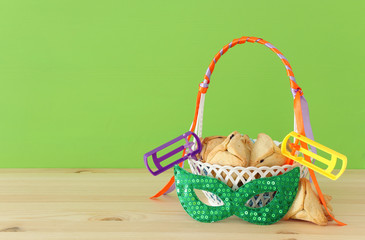 Purim celebration concept (jewish carnival holiday). Traditional hamantaschen cookies in the basket over wooden table