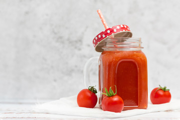 Wall Mural - Fresh tomato juice in jar and cherry tomatoes on light background. With copy space