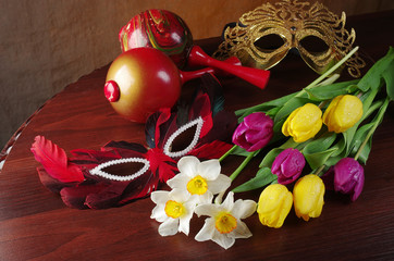 Canvas Print - A bouquet of daffodils and tulips, carnival masks on a wooden table