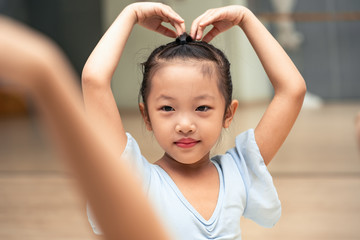 Happy Chinese girl posing at the ballet school and smiling