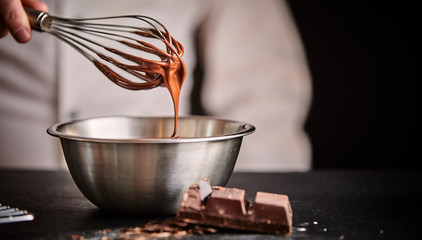 Baker or chef whisking melted chocolate in a bowl