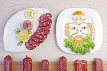 Meat Eating Or Vegetarianism? Plate With Sausages And A Plate With Salad And Vegetables, Decorated As The Face Of A Man With A Beard