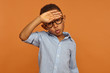 Human facial expressions and body language. Handsome African American male child in round eyeglasses having relieved look, breathing air out, making Phew sound, whiping sweat from his forehead