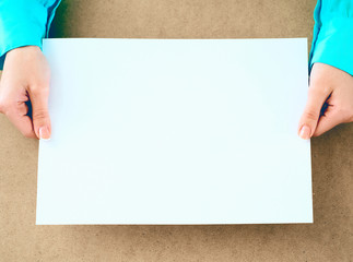 Blank paper in woman's hands waiting for idea or advertising lettering.