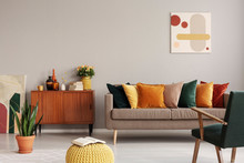 Abstract Painting On Grey Wall Of Retro Living Room Interior With Beige Sofa With Pillows, Vintage Dark Green Armchair And Yellow Pouf With Book