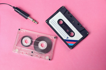 group of two audio retro vintage cassette tape and headphones 80s style on pink background