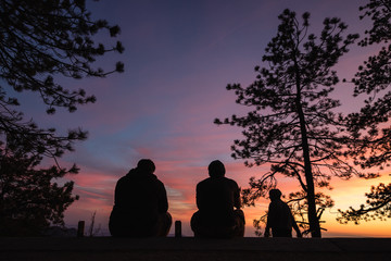 Wall Mural - Friends spending time outdoors enjoying nature, watching the sun set. Vibrant colors in the sky 