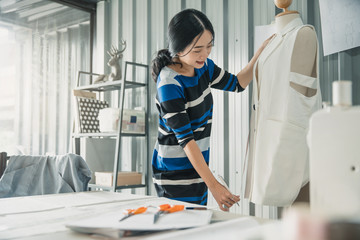 Young female fashion designer working on her designs in the studio. Fashion designer drawing sketches for new collection. Beautiful fashion woman designer drawing in studio .