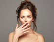 © kiuikson - Surprised woman covered her mouth. Isolated over gray background