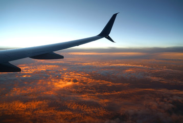 Wall Mural - aerial view of airplane wing above dramatic pyrocumulus sunset cloud
