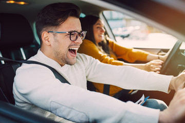 Driving school or test. Beautiful young pregnant woman learning how to drive car together with her instructor.