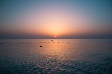 Sunrise over the sea by the shore with rocks in the morning sun.