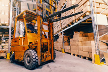 Man Driving Forklift In Warehouse. All Around Shelves And Boxes.