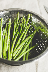 Wall Mural - Washed asparagus in a metal colander on a kitchen table. Preparation vegetarian healthy food.