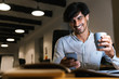 © Drobot Dean - Smiling young man working at the office late at night