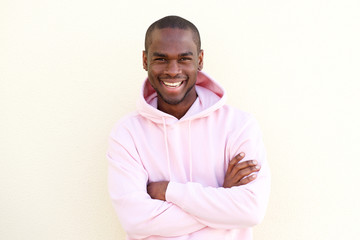 Wall Mural - cool young black man smiling with arms crossed by light wall