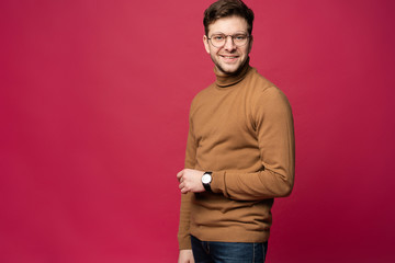 A confident young man in a studio, wearing glasses