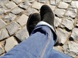 © Clarini - Beine überkreuzt mit schwarzen Lederschuhen