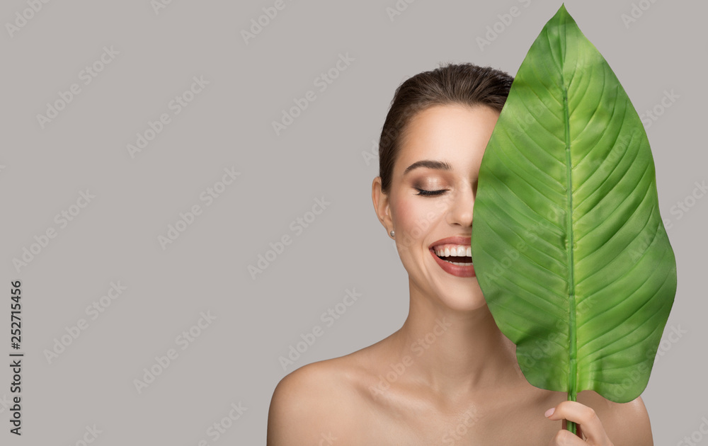 Portrait of woman and green leaf. Organic beauty. Gray background. - obrazy, fototapety, plakaty 