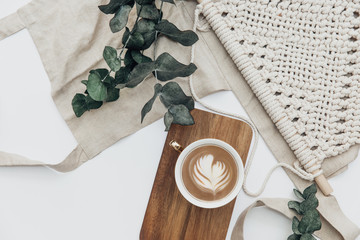 Wall Mural - Flat lay Cup of coffee on wooden serving tray and eucalyptus branch with macrame decoration. Minimal bohemian lifestyle concept for blog and social media