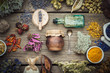 Dry medicinal herbs, plants, roots, ingredients for making herbal medicine drugs, bottle of infusion, jar of ointment, mortar on wooden background.