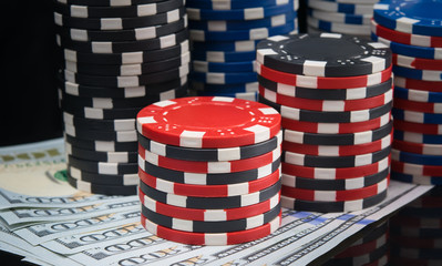 a lot of pyramids of colored chips, for playing in the casino, on the black table and dollars, close-up