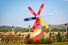 Colorful Windmill Wind Turbine In The Garden With Strawberry Plant And Flower In Pot