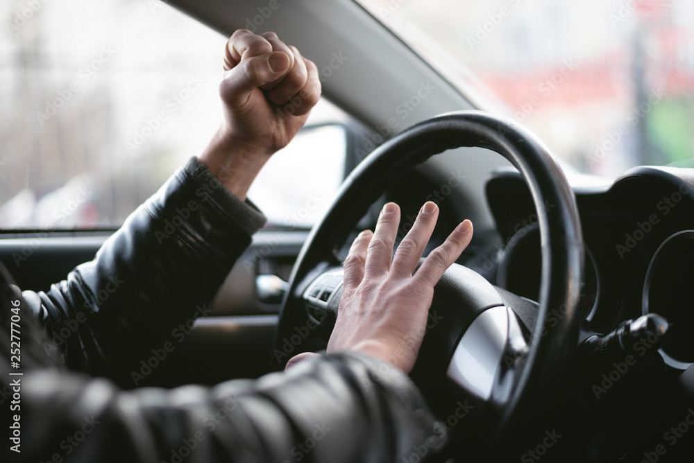 Angry driver is honking and is yelling by sitting of a steering wheel. Road aggression concept. Traffic jam. - obrazy, fototapety, plakaty 