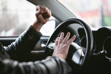 Wall Mural - Angry driver is honking and is yelling by sitting of a steering wheel. Road aggression concept. Traffic jam.