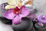 Fototapeta Storczyk - Spa stones and orchid flower on grey background, closeup