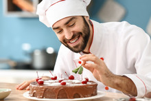 Male Confectioner Decorating Tasty Chocolate Cake In Kitchen