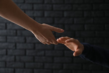 Woman Giving Hand To Depressed Man Against Dark Background. Suicide Prevention Concept