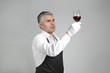 © Pixel-Shot - Mature sommelier with glass of wine on grey background