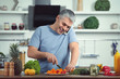 © Pixel-Shot - Mature man talking by phone while cooking dinner at home