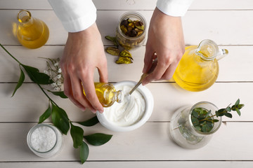 Woman preparing natural cosmetic on white table