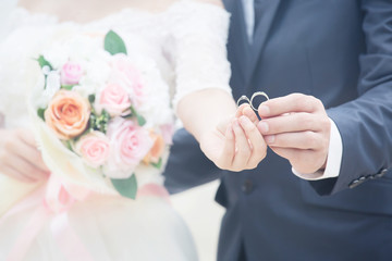 Wall Mural - Close up Groom hand and bride. picture of man and woman newly wed couple hands with wedding rings and holding Bouquet of beautiful a rose flower. lover Wedding ceremony.