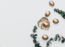 Minimal Flat Lay Gold Easter Eggs With Eucalyptus  Flower On White Background. Top View, Still Life Happy Easter Holiday Concept